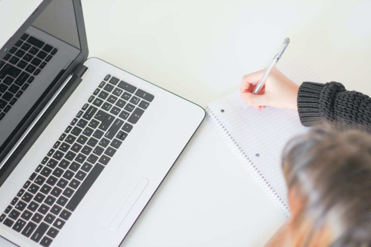 Copywriter che scrive appunti accanto al laptop